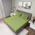 Gres Fern Color Bedsheet With 2 Pillows under a Charcoal Color Bed With Light Lamps on One Side And Photo Frames