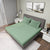 Gres Iceberg Green Color Bedsheet With 2 Pillows under a Charcoal Color Bed With Light Lamps on One Side And Photo Frames