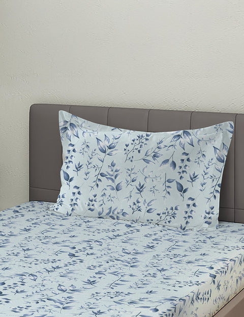 Floral patterned bedsheet with matching pillow on a bed against a plain wall.