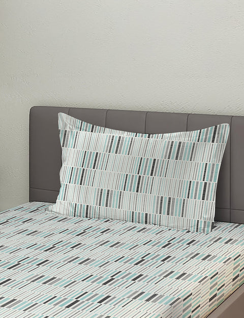 Bed with striped bedding and pillow against a plain wall