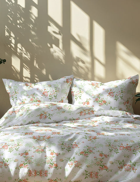 Floral patterned bedding set on a bed with sunlight casting shadows on the wall.