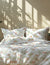 Floral patterned bedding set on a bed with sunlight casting shadows on the wall.