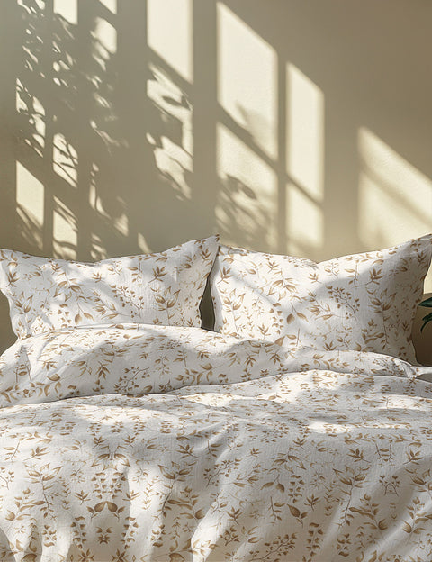 Floral patterned bedding set on a bed with pillows sunlight casting shadow