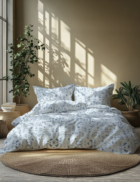 Bedding set with floral pattern on a bed in a room with plants and natural light.