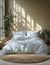 Bedding set with floral pattern on a bed in a room with plants and natural light.