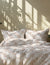 Striped bedding set on a bed with sunlight casting shadows on the wall.