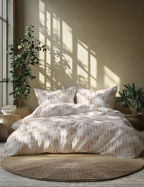 Neatly made bed with striped bedding in a sunlit room with plants