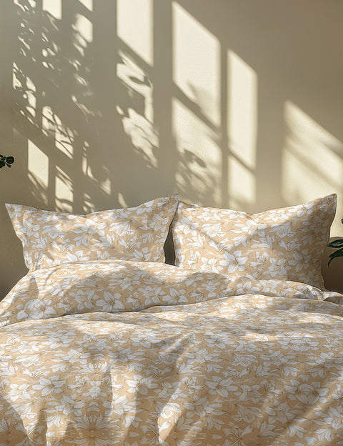 Floral patterned bedding set on a bed with sunlight casting shadows on the wall.