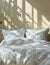 Striped bedding set on a bed with sunlight casting shadows on the wall.