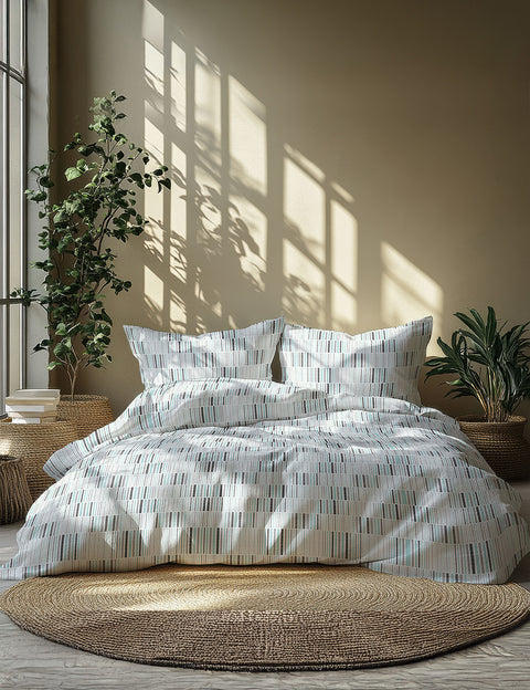Bed with patterned bedding in a room with plants and natural light