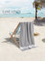 Gray color  towel over a beach chair on a sandy beach with palm trees and ocean in the background, featuring 'Lane Linen' branding.