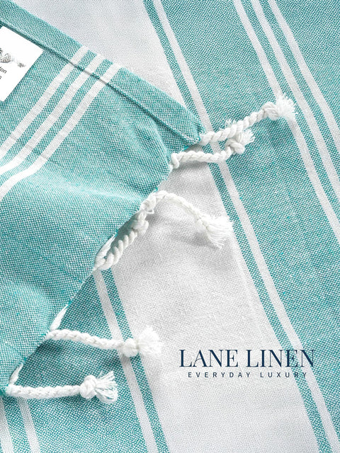 Close-up of a turquoise and white striped fabric with 'Lane Linen' branding.