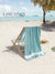 Beach background with a chair hanging with a blue towel, palm tree, and 'Lane Linen' branding