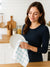 Woman holding a plate and a checkered towel in a kitchen background