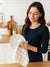 Woman in a kitchen holding a plate and a White Color Beige Striped dish towel