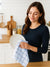 Woman holding a plate and White Color blue stripe kitchen towel in a kitchen background