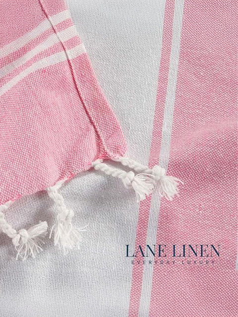 Close-up of a candy pink and white striped towel with tassels, featuring the Lane Linen brand.