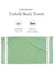 Green Turkish beach towel with packaging details on a white background