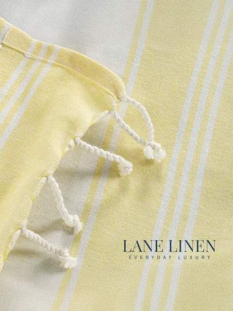 Close-up of a yellow and white striped fabric with frayed edges, featuring 'Lane Linen' branding.