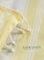 Close-up of a yellow and white striped fabric with frayed edges, featuring 'Lane Linen' branding.