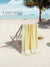 Beach scene with a yellow towel draped over a chair, palm tree, and ocean view with 'Lane Linen' branding.