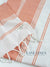 Close-up of a white towel with orange stripes and geometric patterns, branded 'Lane Linen'.
