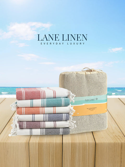 Stack of striped towels and a woven basket with 'Lane Linen' branding against a beach background on a wooden surface