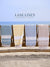 Four towels in blue, beige, and pink hanging on a wooden rack with 'Lane Linen' branding.