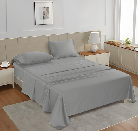 A queen-sized fitted satin sheet set in silver color with 2 Pillows displayed on a bed in a room with a light interior.