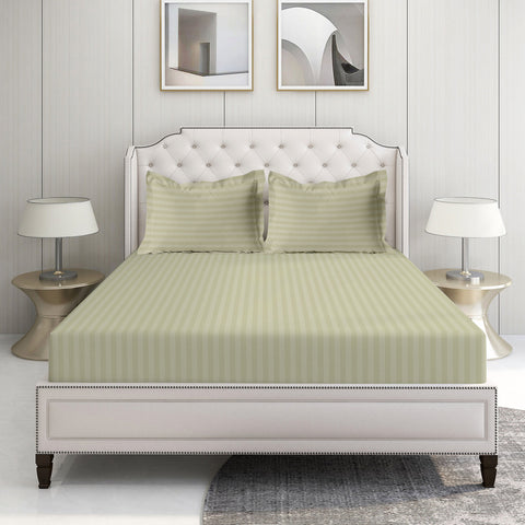 A king-sized fitted sheet with a satin edge and two pillowcases in a bedroom setting, featuring a green stripe pattern on a white background.