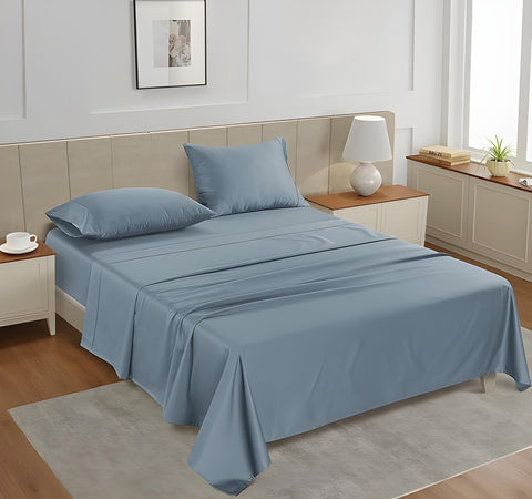 A queen-sized fitted satin sheet set in a Blue color with 2 Pillows displayed on a bed with a pair of pillowcases, in a room with a wooden floor and a light gray carpet.