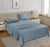 A queen-sized fitted satin sheet set in a Blue color with 2 Pillows displayed on a bed with a pair of pillowcases, in a room with a wooden floor and a light gray carpet.
