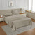 A queen-sized fitted satin sheet set in a Linen color with 2 Pillows displayed on a bed with a pair of pillowcases, in a room with a wooden floor and a light gray carpet.