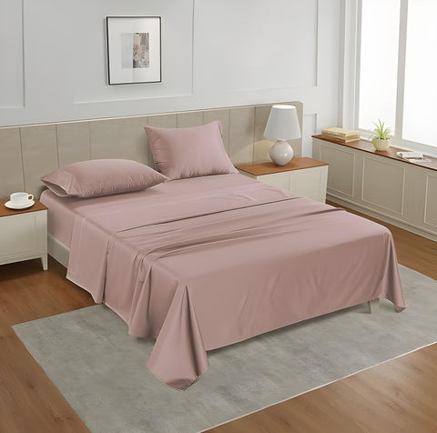 A queen-sized fitted satin sheet set in a Sephia Rose color with 2 Pillows displayed on a bed with a pair of pillowcases, in a room with a wooden floor and a light gray carpet.