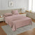 A queen-sized fitted satin sheet set in a Sephia Rose color with 2 Pillows displayed on a bed with a pair of pillowcases, in a room with a wooden floor and a light gray carpet.