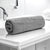 A rolled-up Silver cotton bath towel placed on a white surface in a bathroom setting.