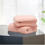 Two folded pink-colored cotton hand towels on a dark surface with a light background.