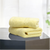 Two folded yellow hand towels on a surface with a window in the background.