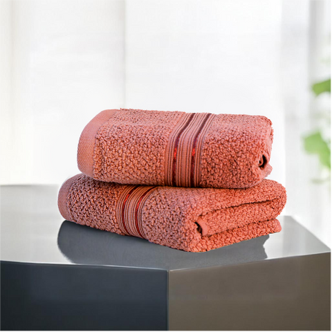 Two folded brown hand towels on a surface.