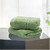 Two green Lane Linen 100% cotton hand towels, highly absorbent, placed on a grey surface with a blurred background.