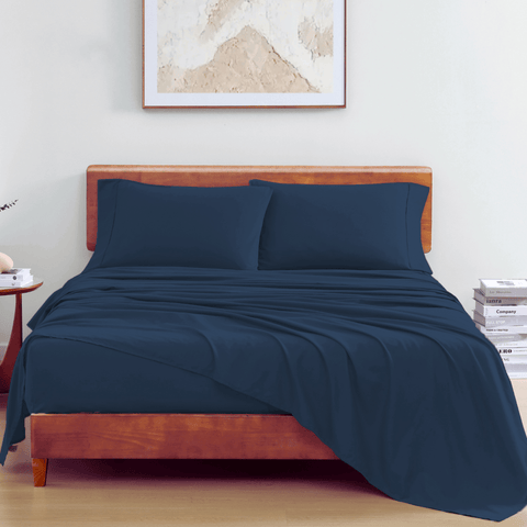 Double sized Bedsheet with 2 Pillows of Blue Color On A Wooden Bed With PhotoFrame In Background