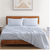 A set of blue polka dot bed sheets with a flat sheet and pillowcases displayed on a bed in a room with minimalist decor.
