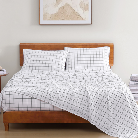 King size bedsheet with 2 pillows on a wooden bed with photoframe in the background